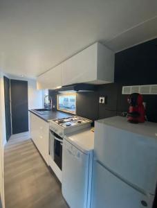 a kitchen with white cabinets and a stove top oven at Mobil-home dans un camping calme et familial chez César in Cambo-les-Bains