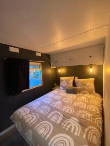 a large bed in a small room with a window at Mobil-home dans un camping calme et familial chez César in Cambo-les-Bains