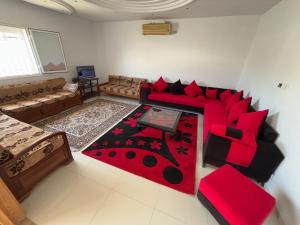 a living room with a red couch and red pillows at Villa blanche sfax in Sfax