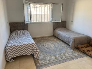 a bedroom with a bed and a window and a rug at Villa blanche sfax in Sfax