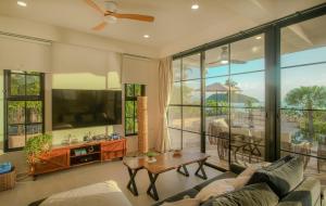a living room with a couch and a tv at Fishman Beachfront Villas in Haad Pleayleam