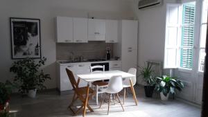 cocina con armarios blancos, mesa y sillas en Apartment24 by Palermo Inn Group, en Palermo