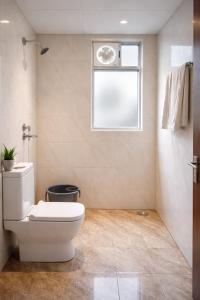 a bathroom with a toilet and a window at OPO Horizon LYRO Hotel , Formerly known as Inde Hotel in Gurgaon +16 photos
