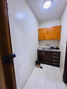 a small kitchen with wooden cabinets and white tiles at Nice Apartment with Sea View in Aqaba +11 photos