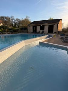 a swimming pool with blue water in front of a house at Gîte de la Bastide de Domme in Domme