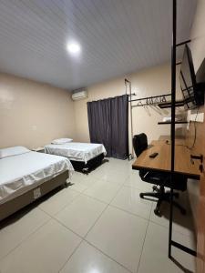 a room with two beds and a desk with a computer at Pousada G3 in Presidente Figueiredo