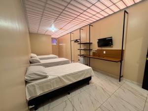a room with three beds and a television in it at Pousada G3 in Presidente Figueiredo
