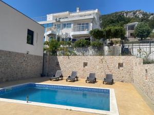 a swimming pool with lounge chairs and a house at Stone Villa in Zagrađe