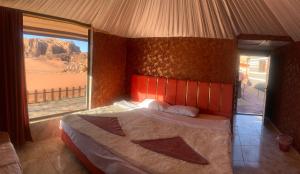 a bedroom with a large bed with a view of the desert at Hillawi Private Desert Camp in Aqaba
