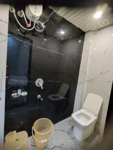a bathroom with a white toilet and a black wall at Hotel Mukhiya Palace in Ujjain