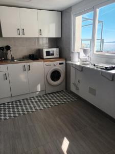 a kitchen with a washing machine and a microwave at Apartamento Bahía Sol in Rincón de la Victoria