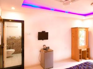 a room with a toilet and a tv on the wall at Veronica By The Beach Calangute in Calangute