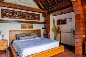 a bedroom with a bed in a room with wooden ceilings at Villa AMPO unique Gazebo Flat in Munggu