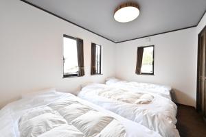 a bedroom with white sheets on the bed at Manabi-WAN Takayama in Takayama