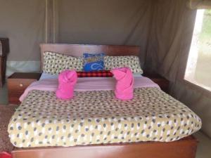 a bed with pink shoes on top of it at Odupoi Lodge in Maji Moto +19 photos