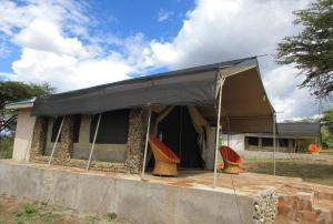a house with a tent with chairs under it at Odupoi Lodge in Maji Moto