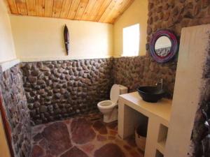 a stone walled bathroom with a toilet and a sink at Odupoi Lodge in Maji Moto
