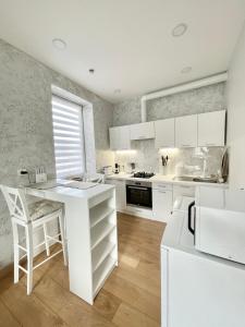 a white kitchen with white cabinets and a table at Rami studio apartment in Panevėžys