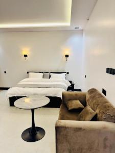 a bedroom with a bed and a couch and a table at الشموخ بارك إن in Z̧alim