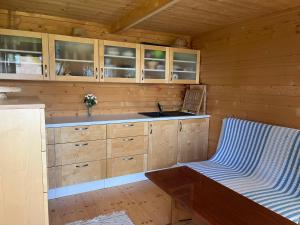 a kitchen with wooden cabinets and a sink and a bench at Srub u Hadiny in Pelhřimov