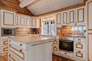 a kitchen with white cabinets and a wooden ceiling at Eksklusiv tømmerhytte Spa Panoramautsikt in Aurdal