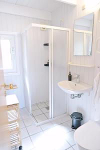 a white bathroom with a shower and a sink at Bork Cozy Cottage in Hemmet +26 photos