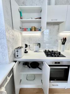 a kitchen with white cabinets and a stove at Rami studio apartment in Panevėžys
