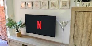 a tv on a wall with a letter n on it at Comarruga Playa apartamento con piscina in Comarruga