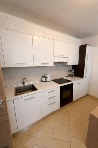 a kitchen with white cabinets and a sink at Aldi APARTMENTS in Lezhë