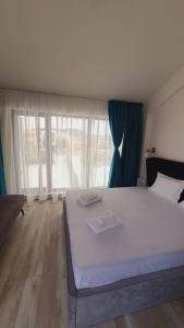 a bedroom with a large white bed in front of a window at Sunny Beach Potos in Potos
