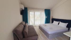 a bedroom with a bed and a couch and a window at Sunny Beach Potos in Potos