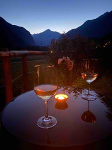 two wine glasses sitting on a table with a candle at Holiday accomodation appartamento in seminterrato in Coglio