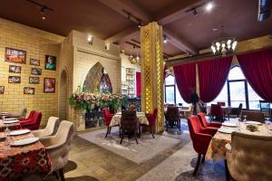 a restaurant with tables and red chairs and windows at Dashli Gala Hotel Ganja in Ganja