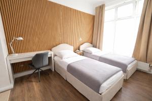 two beds in a room with a desk and a chair at BASSWOOD ROOMS in Bremen
