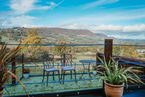 a balcony with two chairs and a table and a view at Hatterall View Glamping Pod in Abergavenny