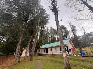 a house with a green roof and a group of trees at Lala Ji coasy cottage in Pahalgām