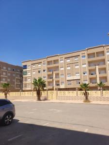 a car parked in front of a building with palm trees at appartement NADOR wifi gratuit clima mobile in Selouane