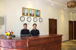 dos hombres parados detrás de un escritorio con un portátil en Le Water Villa en Siem Reap