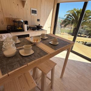 a wooden table with cups and saucers on it at Costa Lodge Pichilemu in Pichilemu