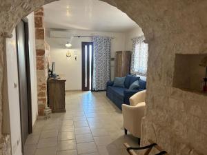 a living room with a blue couch and a stone wall at Il Borgo Delle Querce Villa Fichi Piscina privata in Martina Franca