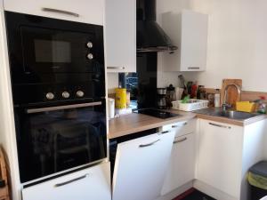 a kitchen with white cabinets and a black oven at A la ferme chez Christian in Escaudoeuvres