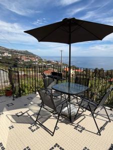 a table and chairs with an umbrella on a patio at Casa da Quinta in Estreito da Calheta