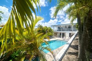 a villa with a swimming pool and palm trees at villa vue mer logements indépendants piscine privative in Grand-Bourg