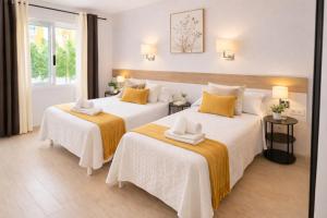 two beds in a hotel room with white and yellow pillows at Hotel Ancla in Oropesa del Mar