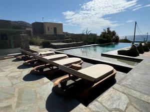 a row of lounge chairs sitting next to a swimming pool at Sea & Stone Villas in Koundouros