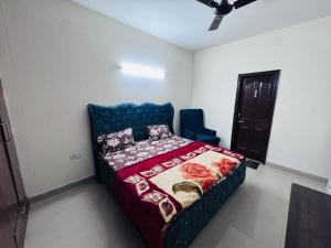 a bedroom with a bed and a blue chair at Homely stayy in Mohali