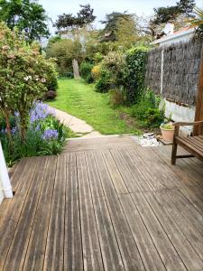 a wooden deck with a bench in a garden at Agréable studio indépendant proche mer in Saint-Hilaire-de-Riez