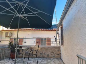 a table and chairs under a blue umbrella on a balcony at Rodomelo Cute Studio 3 in Leonidio +4 photos