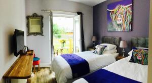 a bedroom with two beds and a painting on the wall at Angel Cottage in Drymen