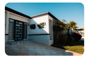 a white house with a black door and plants on it at La Posadita in Carolina